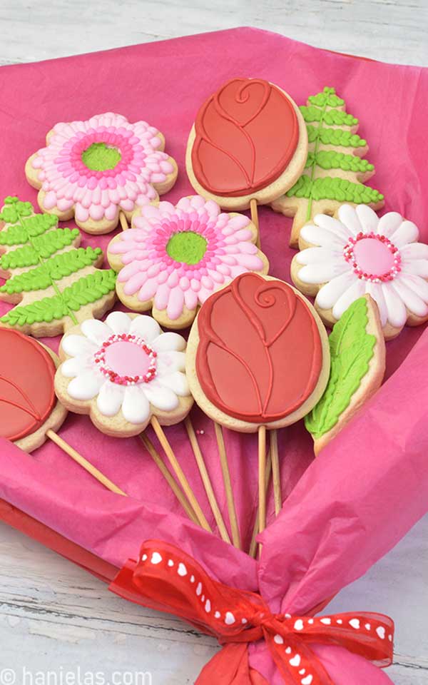 Decorated flower cookies on bamboo sticks arranged into a flower bouquet.