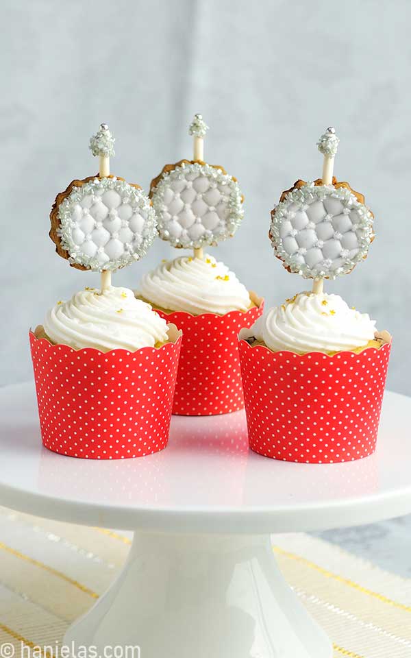 Cupcakes in red liners with a white buttercream on a cake stand.