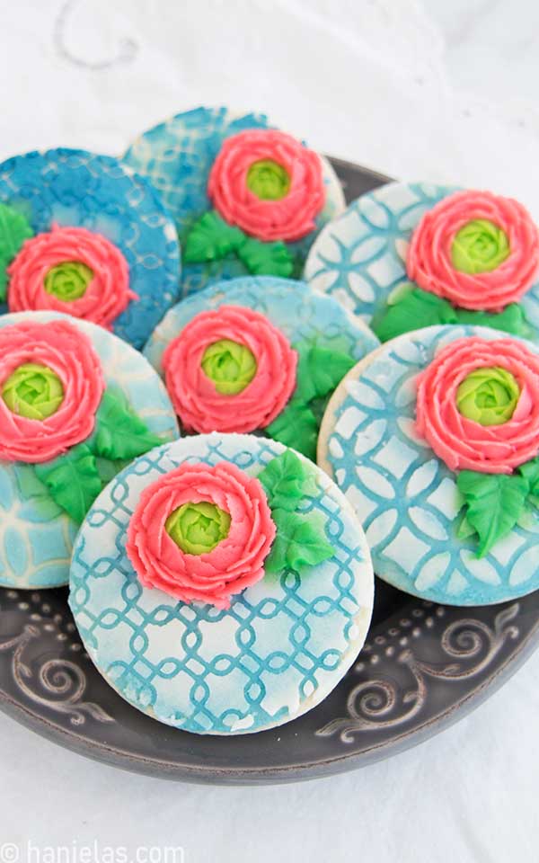 Round cookies decorated with frosting and piped ranunculus flowers.