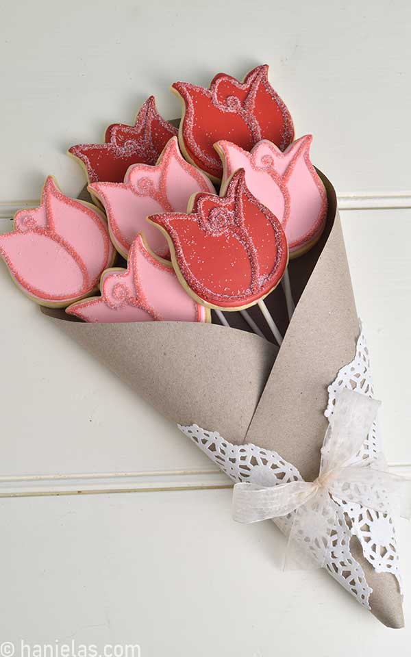 Dekorierte Rosenkekse, eingewickelt in braunes Bastelpapier und weißes Deckchen.