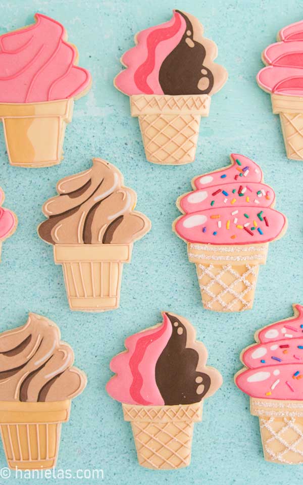 Ice cream cone cookies decorated with royal icing displayed on teal background.