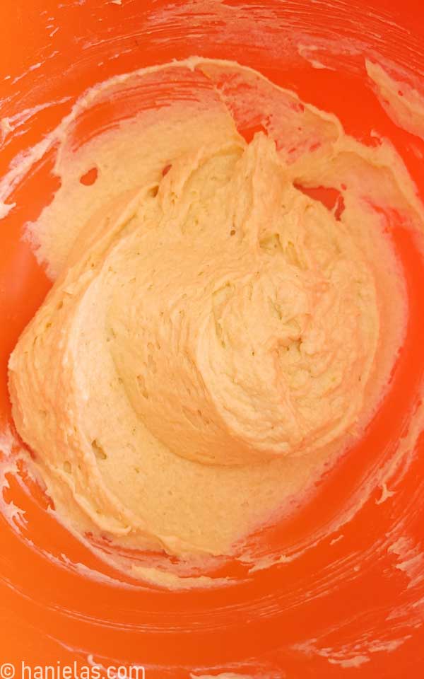 Orange mixing bowl with muffin batter.