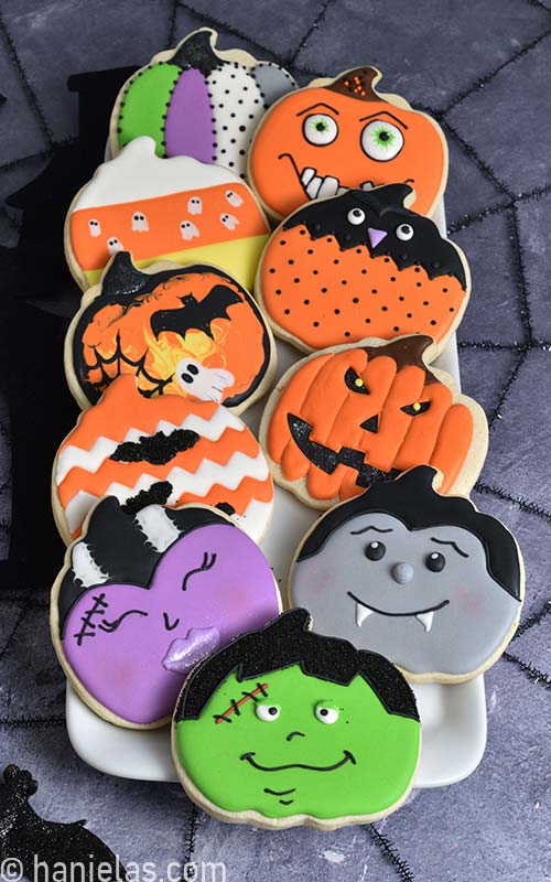 Decorated pumpkin shaped cookies on a white plate.