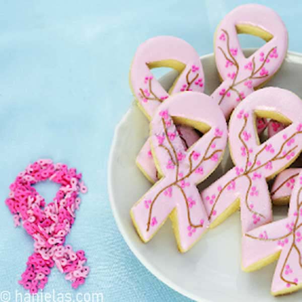 Ribbon cookies decorated with pink icing on a white plate.