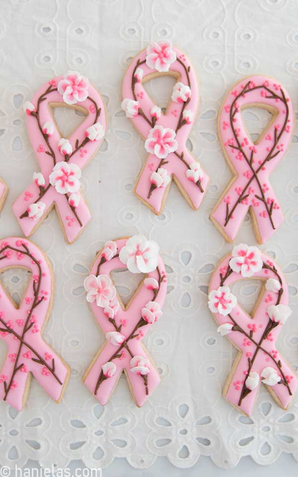 Decorated cookies in a shape of ribbons on a white tablecloth.