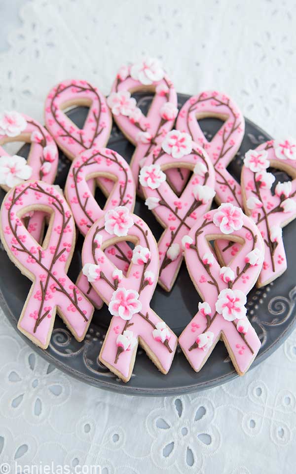 Cookies decorated with icing and cherry blossom flowers on a gray plate.