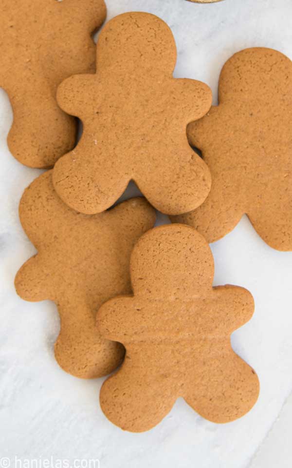 Baked gingerbread men cookies, undecorated stacked on a white background.