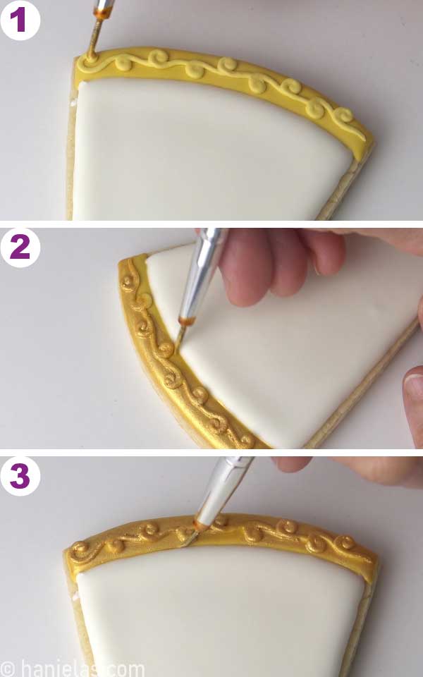 Hand holding a brush, painting dry icing with gold edible paint.