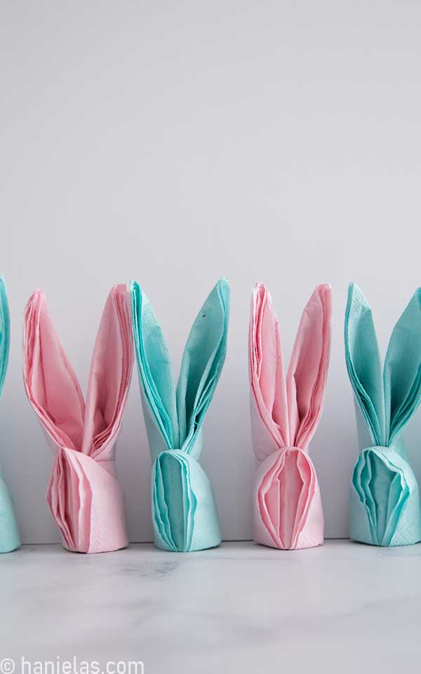 Pink and blue bunny napkins lined up against a white background.