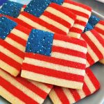Cookies in a shape of American flag, stacked on a light blue plate.