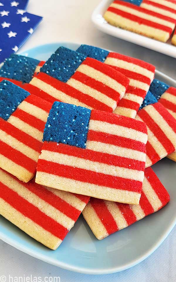 Cookies in a shape of American flag, stacked on a light blue plate.
