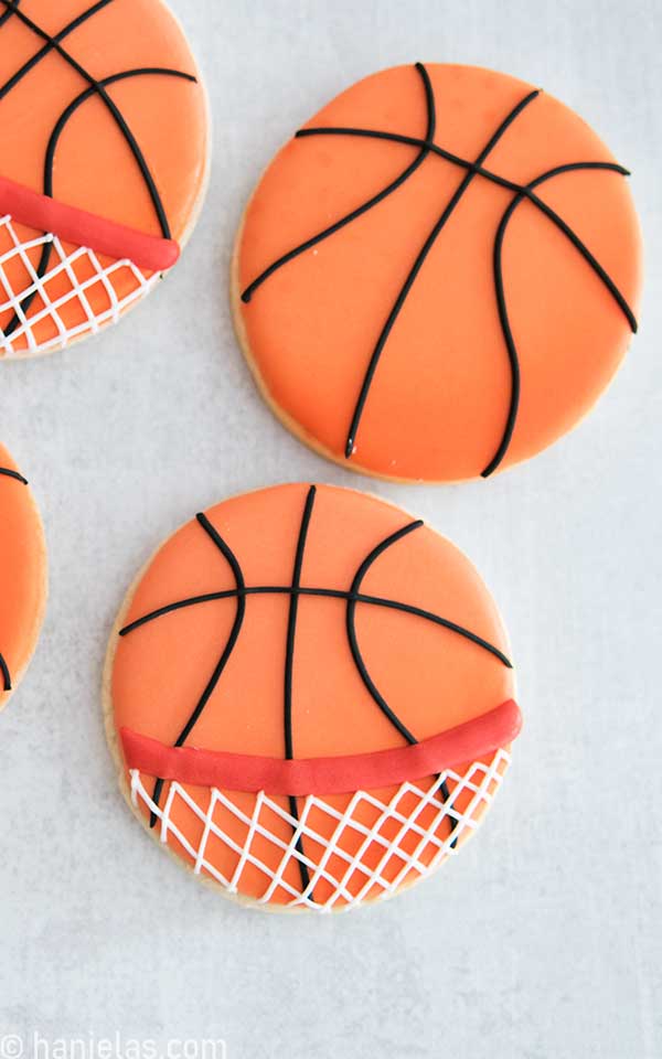 Round cookie decorated with orange and black icing to make them look like basketballs.