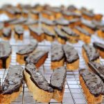 Cookies dipped in chocolate on a cooling rack.