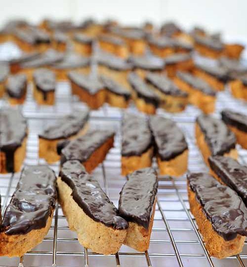 Cookies dipped in chocolate on a cooling rack.
