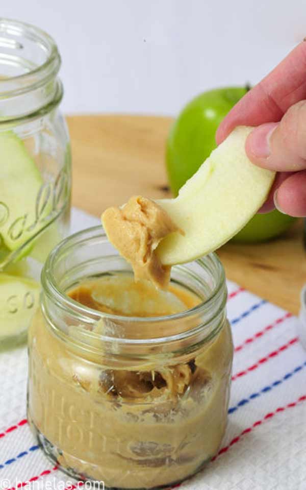 Hand holding an apple slice with a dip.