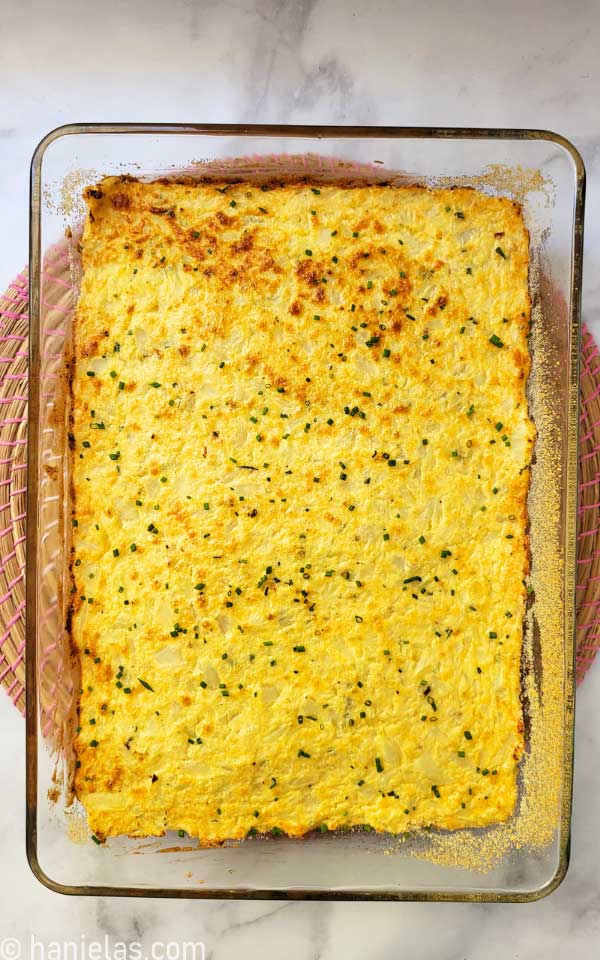 Golden brown surface of casserole dish in a glass baking pan.