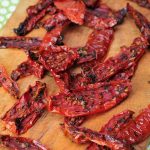 Dried roma tomatoes slices on a cutting board.