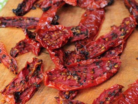 Dried roma tomatoes slices on a cutting board.