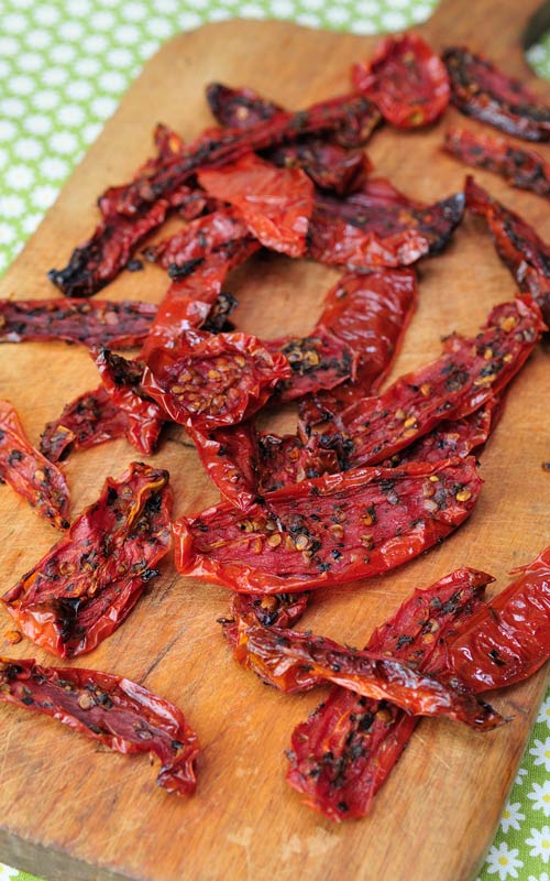 Dried roma tomatoes slices on a cutting board.