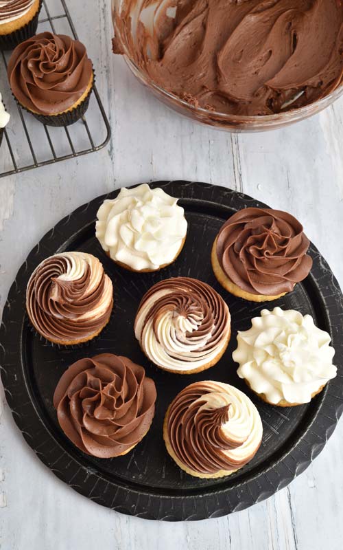 Cupcakes frosted with chocolate and vanilla frosting on a plate.