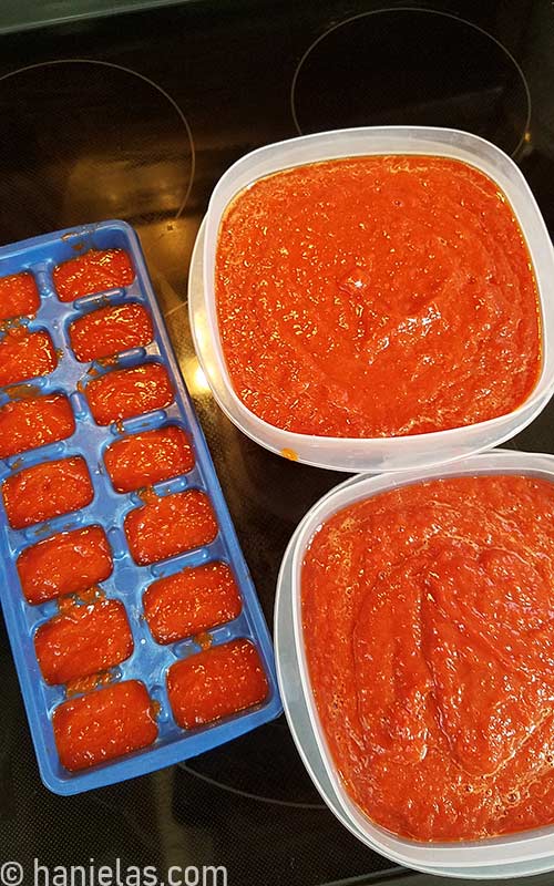 Plastic container filled with pepper puree on a kitchen stove.