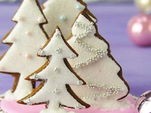 Tree cookies decorated with white icing glued on a round base standing up.