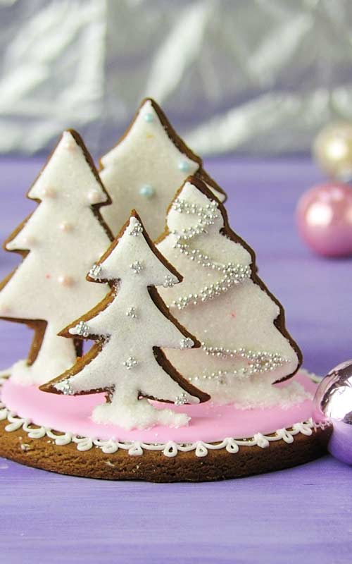 Tree cookies decorated with white icing glued on a round base standing up.