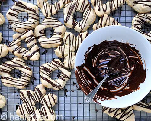 Cookies on a cooling rack drizzled with melted chocolate.