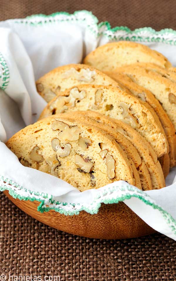 Golden yellow baked and sliced cookies a basket lined with white napkin.