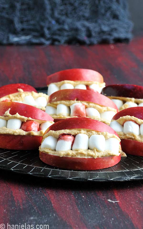 Black plate with apple slices filled with peanut butter and marshmallows.