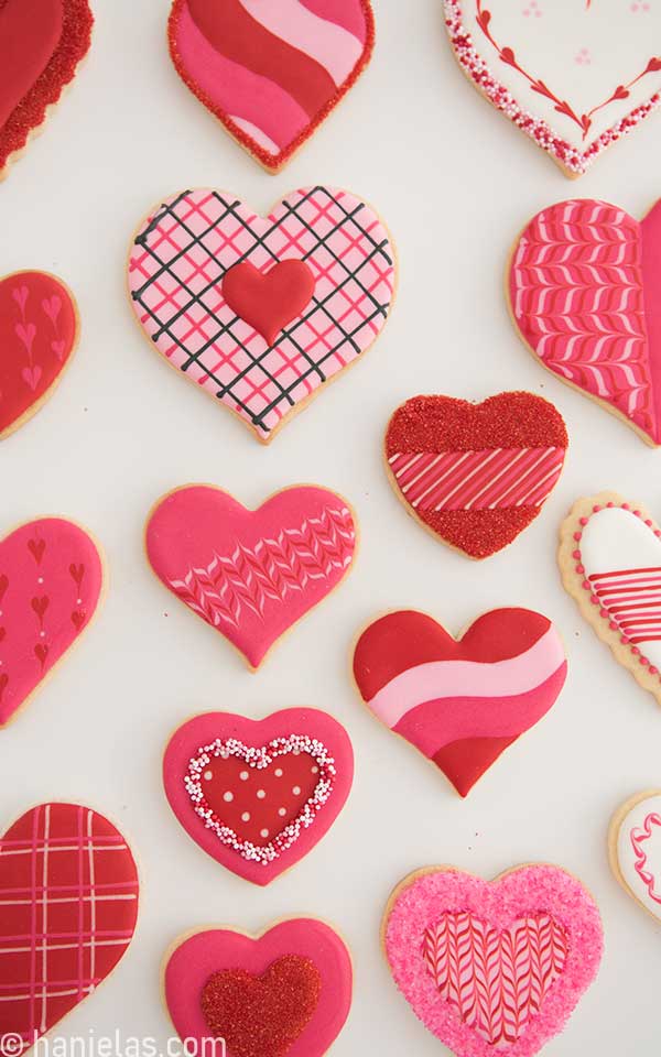 Cookies decorated with pink red and white royal icing on a white background.