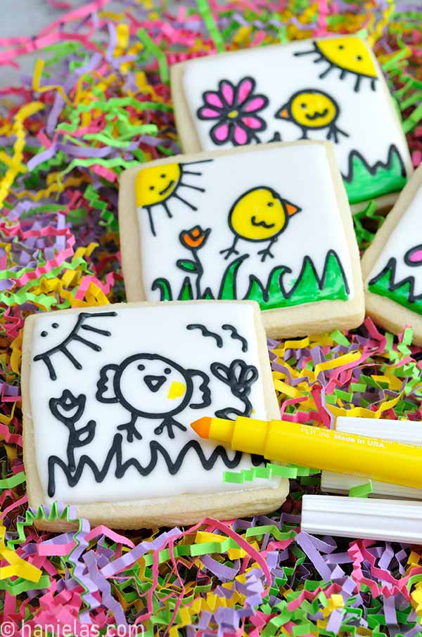 Yellow edible marker with the tip exposed sitting on top of the undecorated cookie.