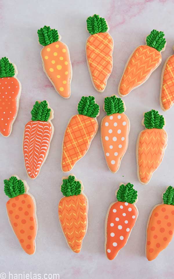 Cookies in the shape of a carrot decorated with royal icing.