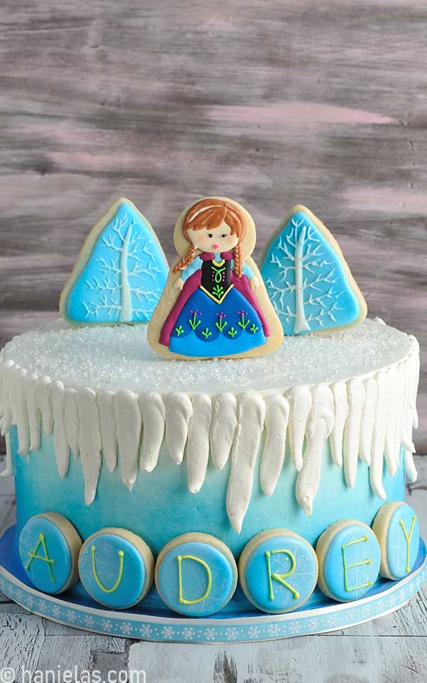 Blue winter style cake decorated with cookie pops toppers.