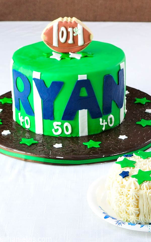 Green football style cake decorated with brown football cookie pop.