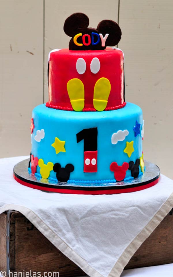 Cake decorated with Mickey Mouse ears cookie on a strick.