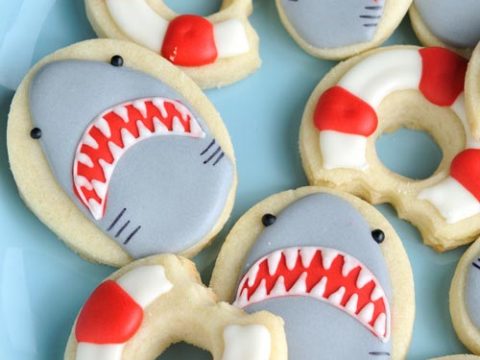 Decorated shark cookies and lifebuoy cookies on a plate.