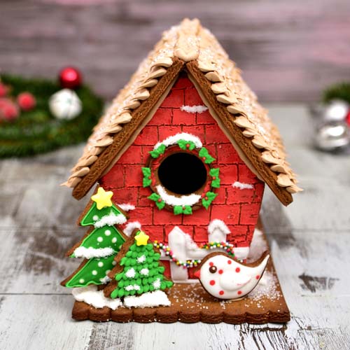 Decorated gingerbread birdhouse displayed on a table.