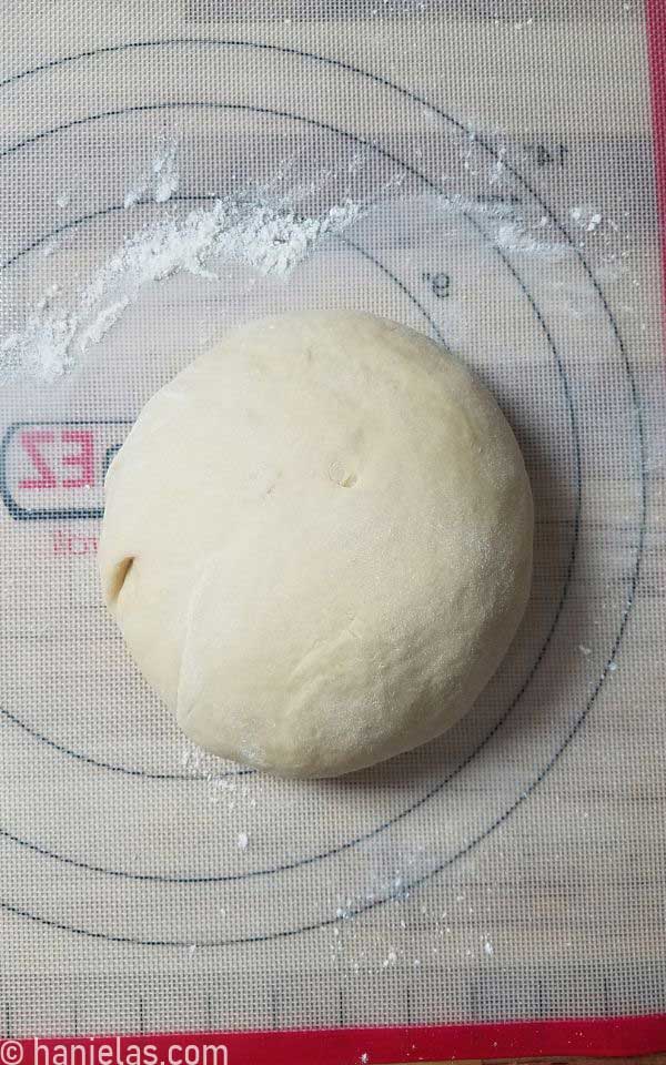 A ball of bread dough on a silicone mat.