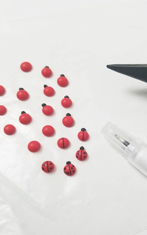Mini ladybugs piped on a wax paper.