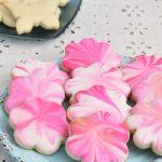 Pink marbled flower shaped cookies on a plate.