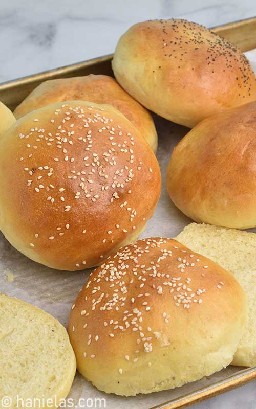 Golden brown hamburger buns on a baking sheet.