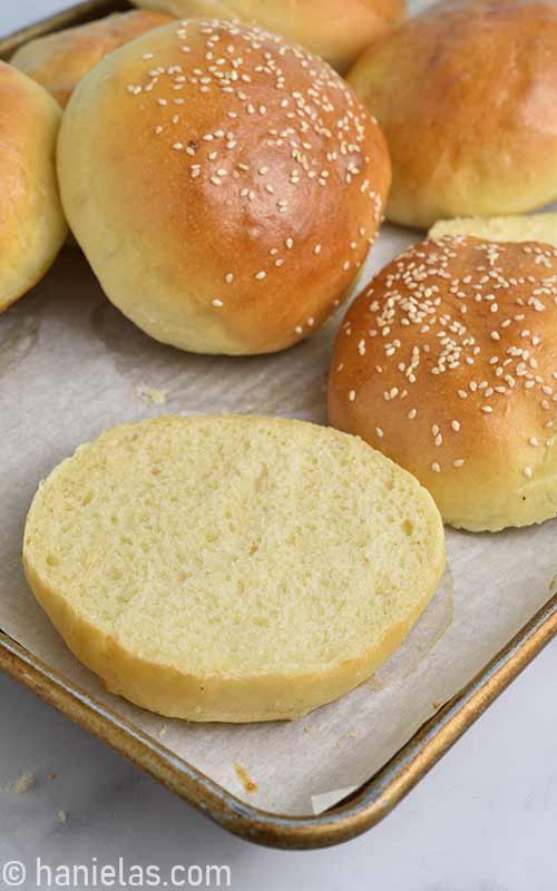 Golden brown hamburger buns on a baking sheet.