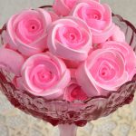 Pink meringue rose cookies in a pink glass bowl.