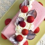 Strawberry mousse cake decorated with chocolate leave and whipped cream swirls.