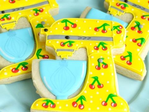Yellow stand mixer cookies with cherry pattern on a blue plate.
