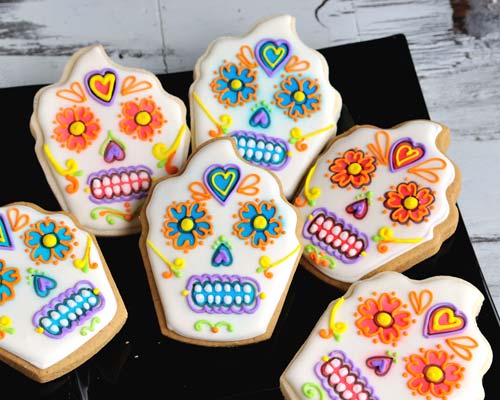 Decorated day of the dead cupcake cookie displayed on a black plate.