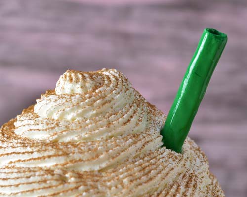 Details of green drinking straw inserted into a cake.