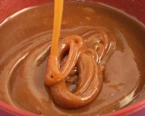 Pouring caramel sauce into a bowl.