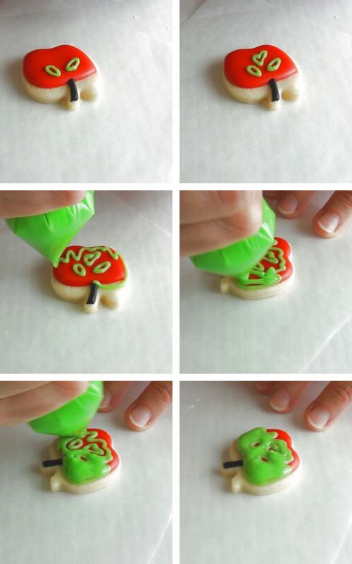 Decorating red apple cookie with green royal icing.